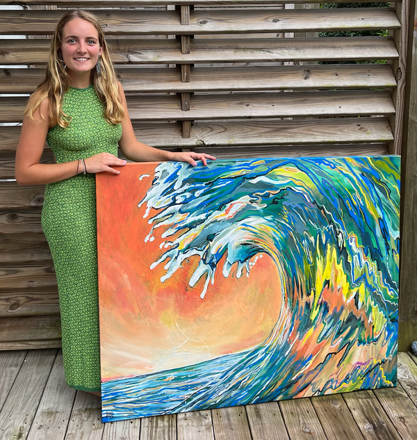 Woman holding a painting of a colorful wave on a wooden deck